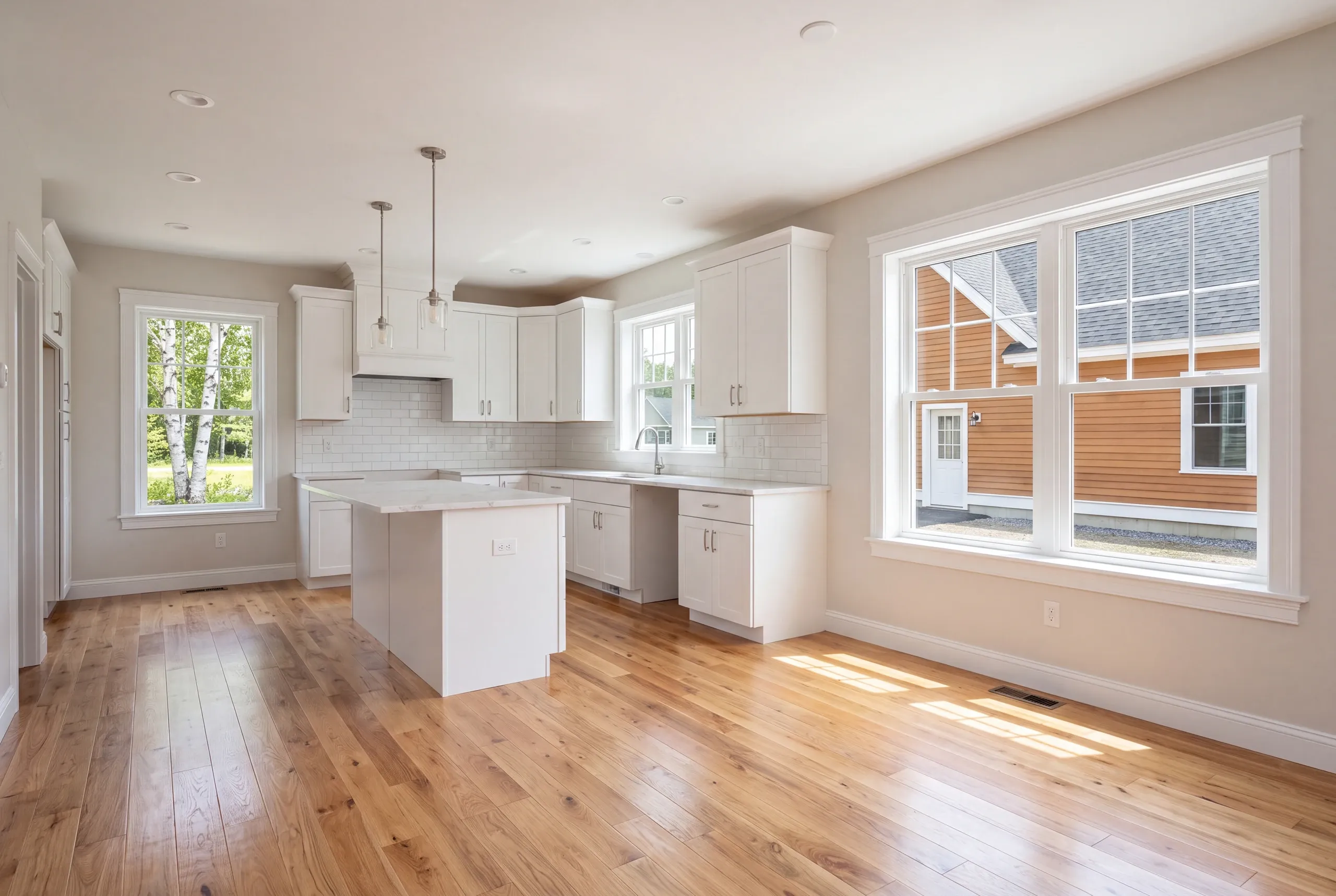 Open kitchen and dining area in a newly finished Waterville home with wide plank floors