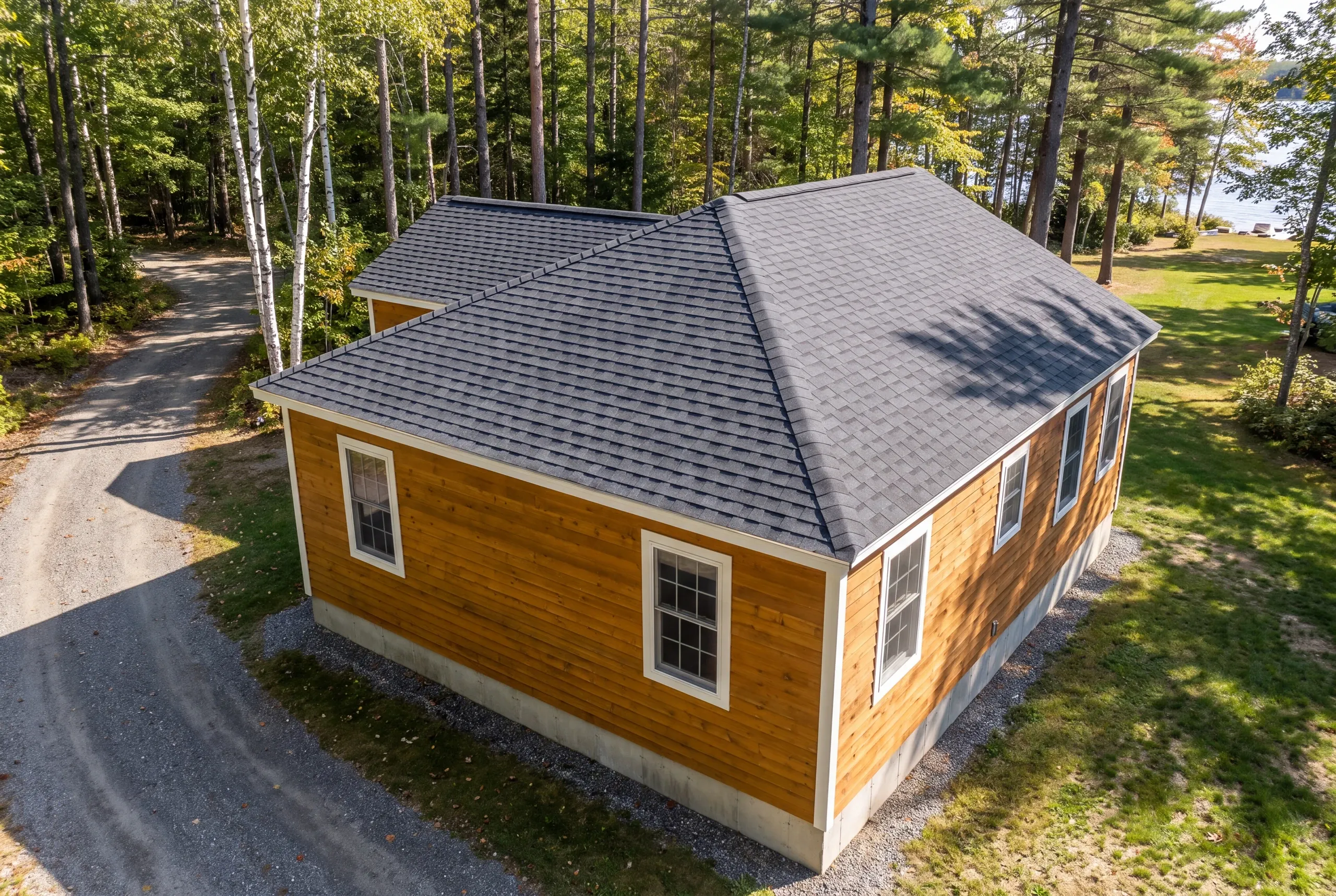 Roofing contractor Belgrade, ME delivering material down a narrow camp road